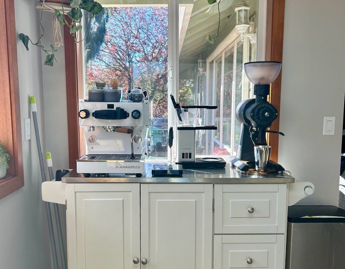 Counter with espresso and pour over coffee makers along side coffee grinder